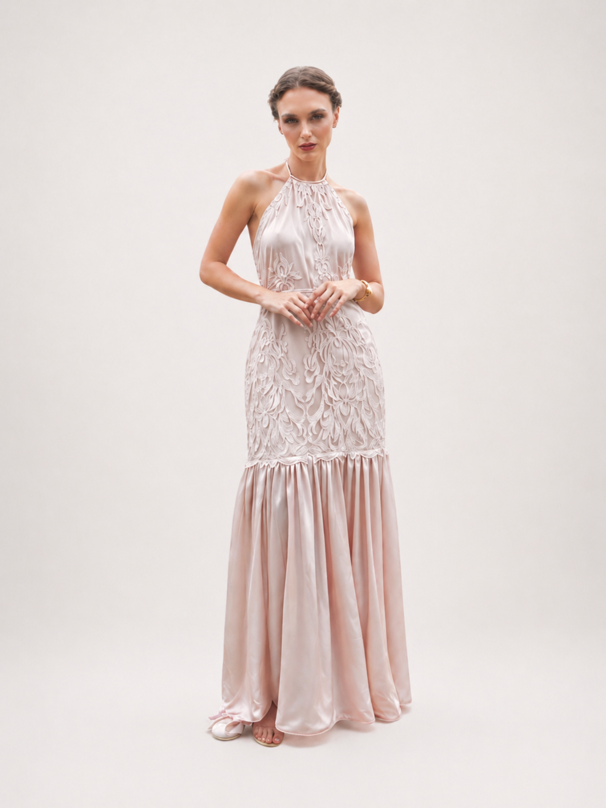 Woman wearing a long, elegant dress with lace top and satin skirt on a white background